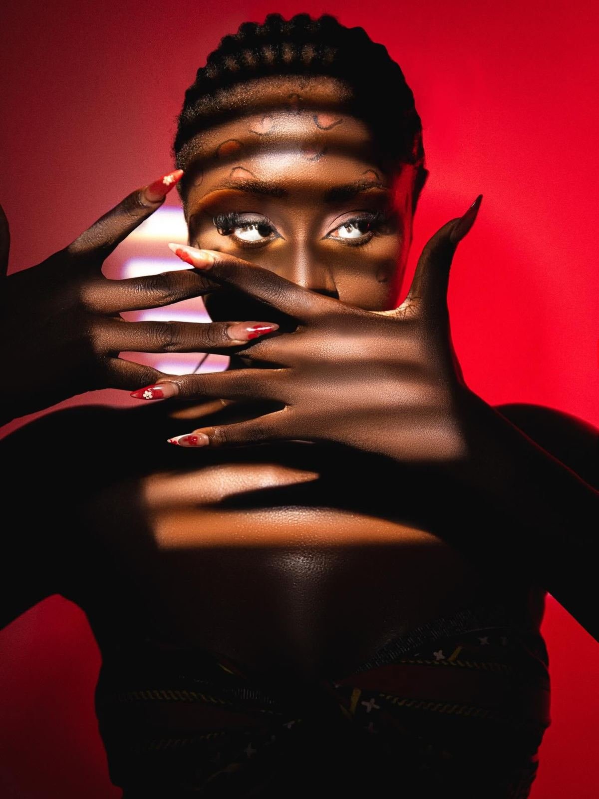 Portrait de studio, mains encadrant le visage sur fond rouge